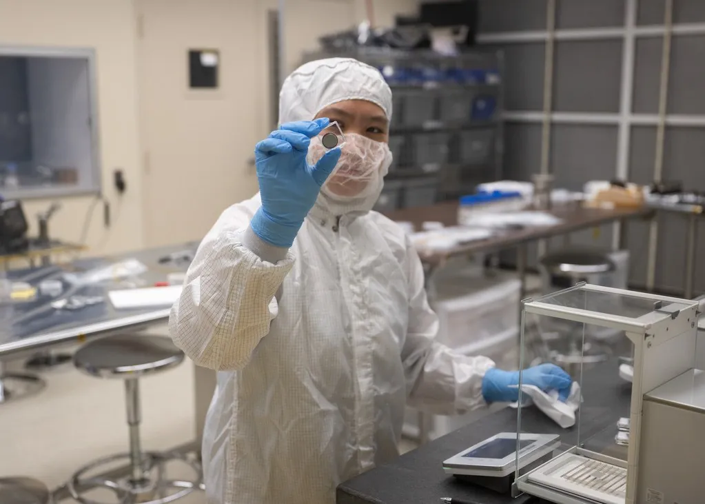 Nike Lin, a support engineer/technician on the thermal vacuum team, holds up a battery.