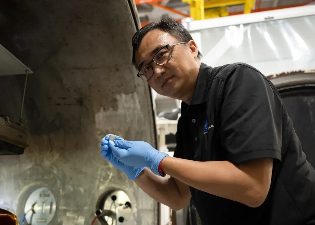 Yi Lin, SPEARS testing and research lead at NASA Langley, holds one of the small coin-cell batteries that had just undergone thermal vacuum testing.