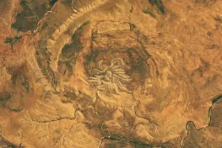 Several short, light-colored rocky ridges radiate out from a central point amid an orange and tan desert landscape.