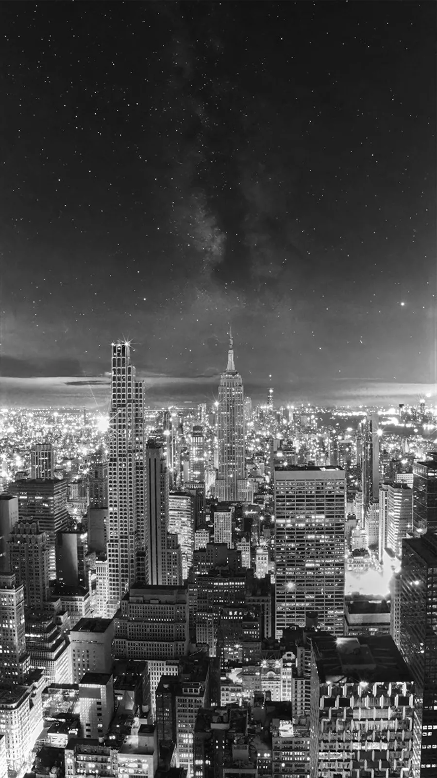 A black and white view of the Manhattan skyline merges into a night sky with stars and a visible, though faint, Milky Way. Please see explanation for more details.