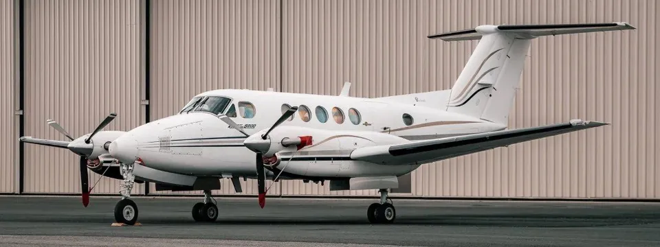 A two engine aircraft sitting in front of a hangar.