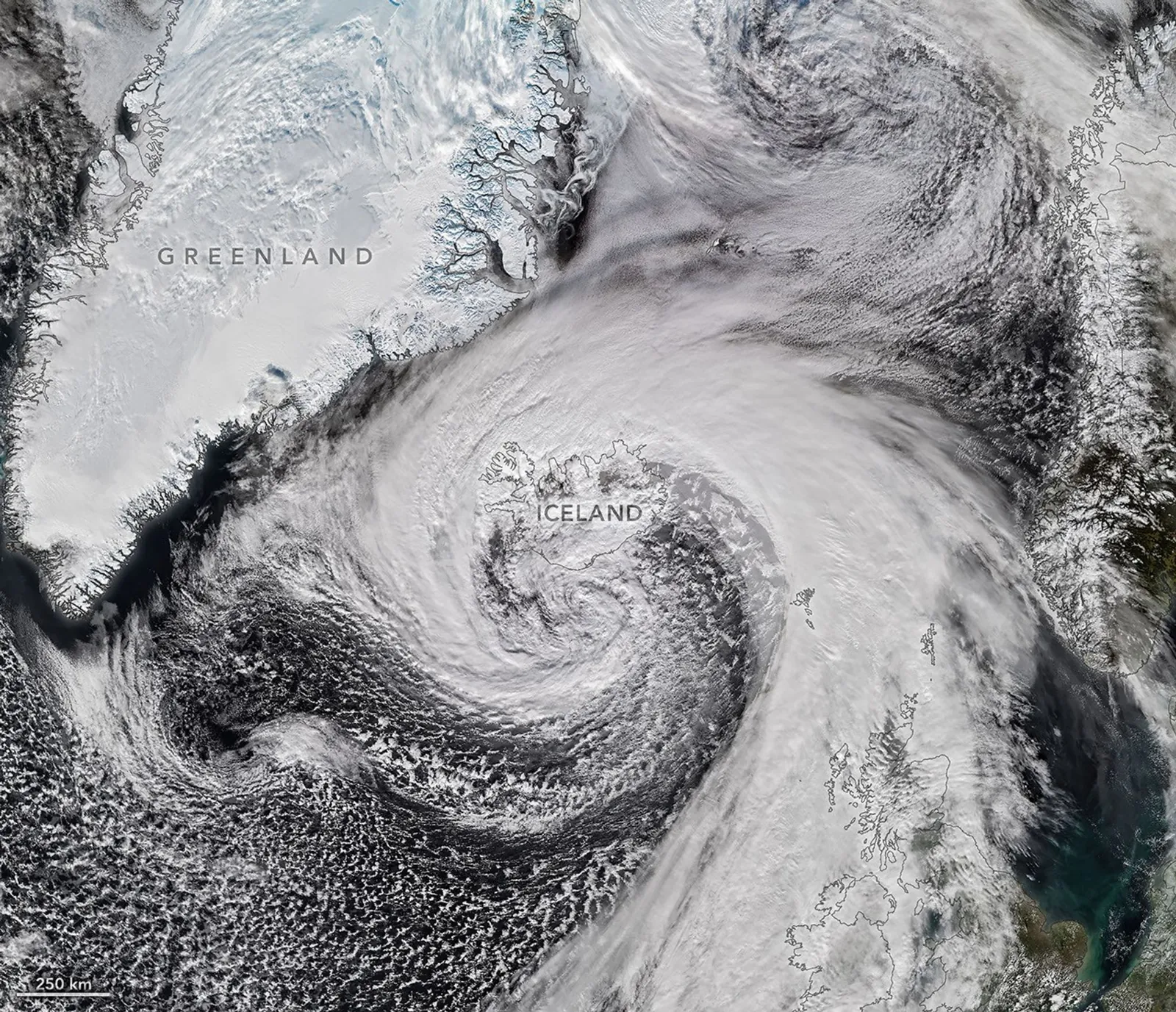 Storm clouds in an expanding spiral are centered near southern Iceland. The system extends across the North Atlantic from Greenland to the UK.